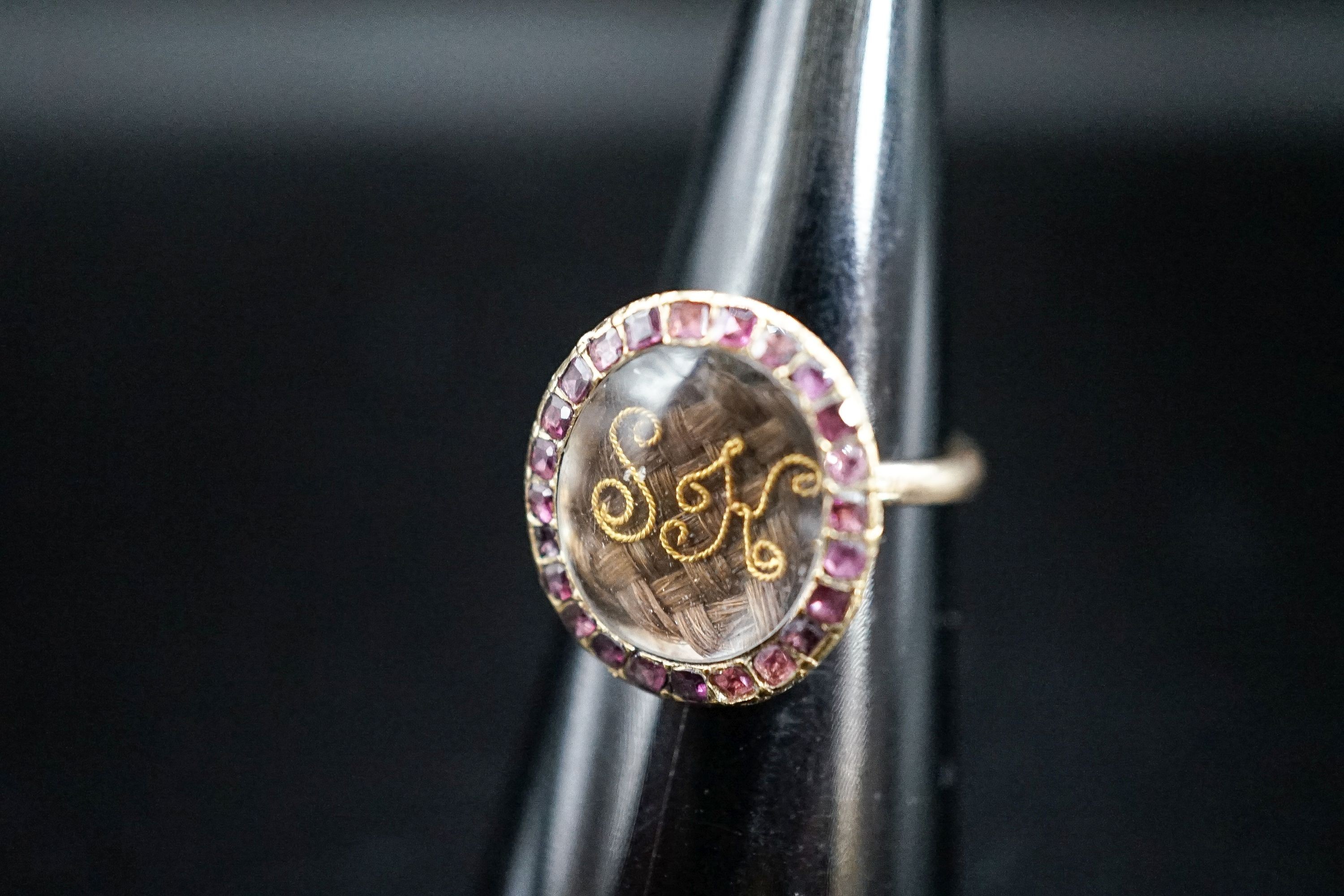 A 19th century yellow metal and gem set mounted glazed mourning ring, with 'S.H.' initialled above plaited hair, size I, gross weight 2.9 grams (adapted).